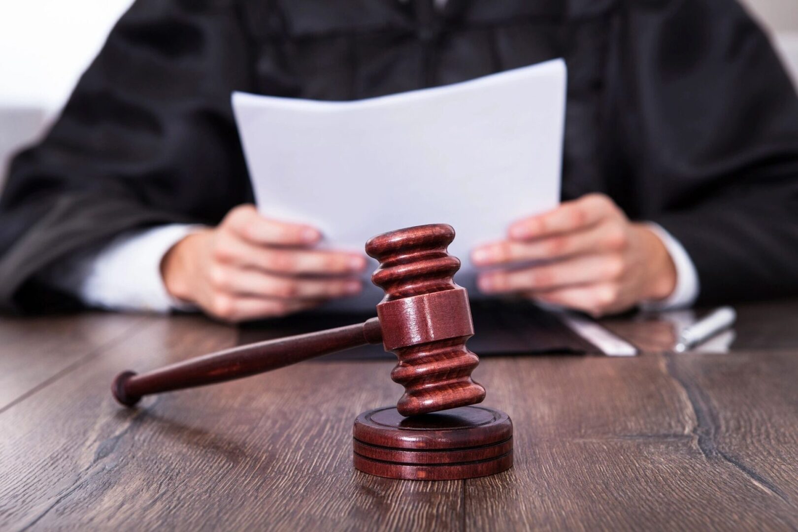 A judge holding a paper and a wooden gavel